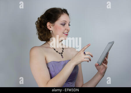 Jolie Jeune femme portant robe sans bretelles formelle à l'aide de tablet Banque D'Images