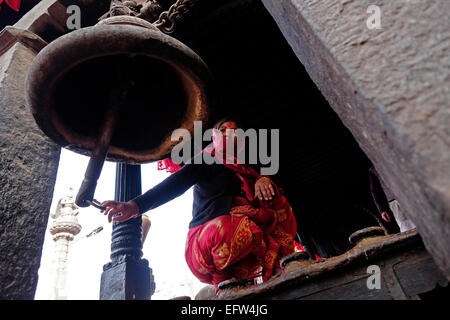 Une femme népalaise sonne la cloche de l'ancienne, Magella temple construit sous le règne du Roi Yaksha Malla (1428 A.D. - 1482 A.D.) dans Dattatrayta square dans la ville de Bhaktapur, également connu sous le nom de Khwopa au Népal Banque D'Images