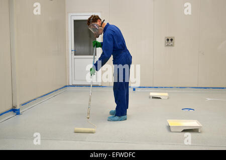 Un commerçant rolls une couche finale d'époxy clair produit sur le plancher d'un bâtiment industriel Banque D'Images