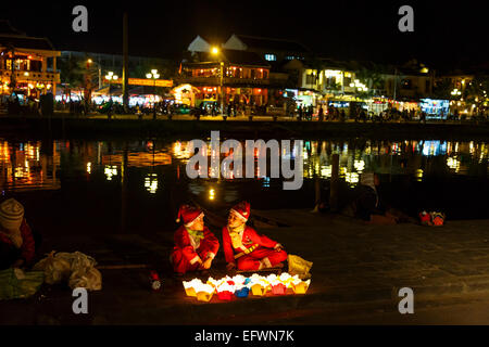 Enfants habillés en Père Noël vente de bougies flottantes, Hoi An, Vietnam. Banque D'Images