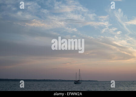 Bateau à voile solitaire dans la mer avec juste après le coucher du soleil Ciel Banque D'Images