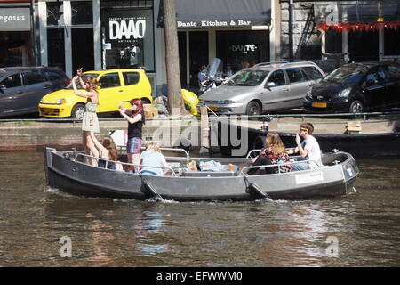 Les jeunes adultes à faire la fête sur un bateau dans un canal à Amsterdam. Banque D'Images