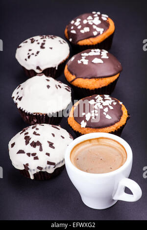 Tasse de café et muffins dans la glaçure sur fond sombre Banque D'Images