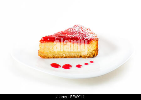 Un morceau de gâteau de fruit sur une plaque blanche avec des gouttes de confiture Banque D'Images