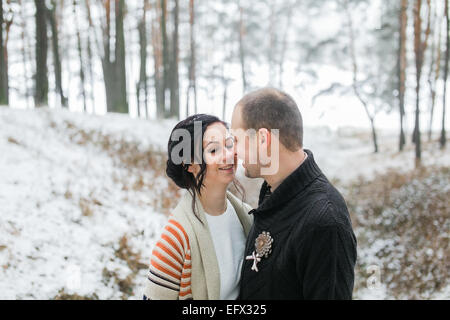 Bride and Groom hugging in snow-covered winter forest Banque D'Images