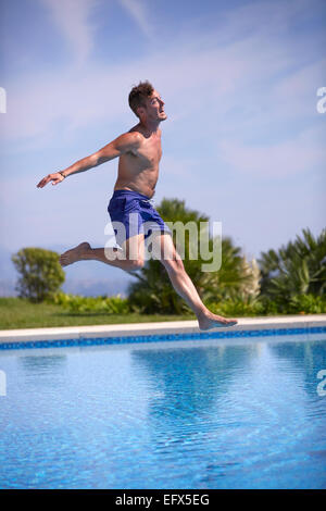 Jeune homme qui saute dans la piscine Banque D'Images