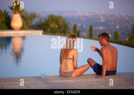 Jeune couple à vous détendre au bord de la piscine dans le sud de la France au coucher du soleil Banque D'Images