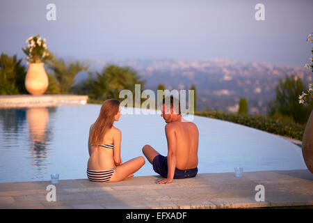 Jeune couple à vous détendre au bord de la piscine dans le sud de la France au coucher du soleil Banque D'Images