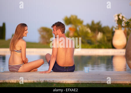 Jeune couple à vous détendre au bord de la piscine dans le sud de la France au coucher du soleil Banque D'Images