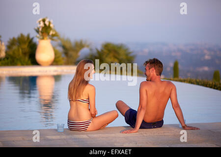 Jeune couple à vous détendre au bord de la piscine dans le sud de la France au coucher du soleil Banque D'Images