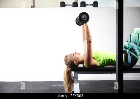 Jeune femme couché sur banc de musculation en salle de sport de la barre de levage de Bell Banque D'Images