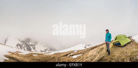 Vue panoramique du jeune homme et tente dans la brume, Alpes bavaroises, Oberstdorf, Bavière, Allemagne Banque D'Images