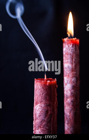 Flamme de bougie soufflée montrant fumer dans un joli fond sombre, d'autres reste allumé avec la flamme de bougie Banque D'Images