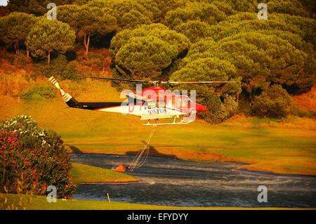 Hélicoptère Bell 412 (immatriculé N167EH) la collecte de l'eau pour la lutte contre les incendies d'un terrain de golf, le lac, le golf de Cabopino Espagne. Banque D'Images