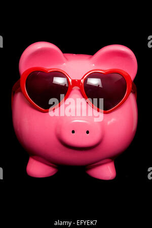 Piggy Bank wearing red heart découpe lunettes Banque D'Images