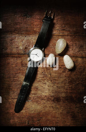 Nature morte à la montre-bracelet et trois pierres sur table en bois. Vue d'en haut. Banque D'Images