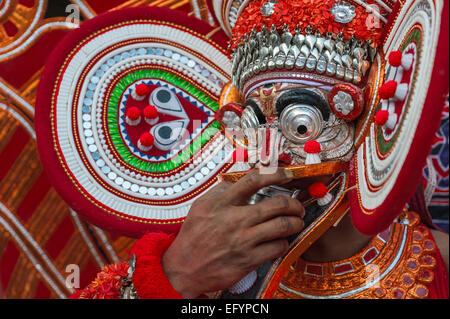 Un artiste interprète ou exécutant toddy des boissons dans le cadre de la performance au cours d'un rituel hindou Theyyam traditionnels de performance, Kerala, Inde. Banque D'Images