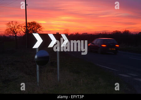 Au coucher du soleil voiture panneau d'avertissement de passage de virage et de sécurité circulaire miroir pour donner aux conducteurs de voir road uk Banque D'Images