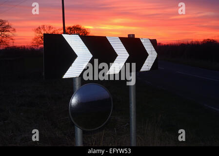 Coucher du soleil par panneau d'avertissement de virage et de sécurité circulaire miroir pour donner aux conducteurs de voir road uk Banque D'Images