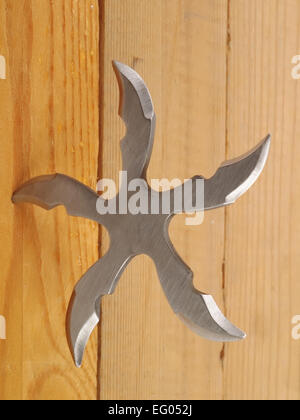 Lame de ninja Shuriken lancer star en planche de bois, studio shot Banque D'Images