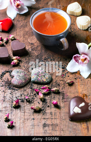 Bonbons de chocolat en forme de coeur avec des roses thé sec et tasse de thé pour la Saint-Valentin. Banque D'Images