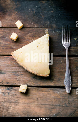 Gros morceau et de petits cubes de fromage belge avec vintage fourchette sur fond de bois. Vue d'en haut. Banque D'Images