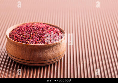 Sumac épices dans un bol en bois sur un fond brun Banque D'Images