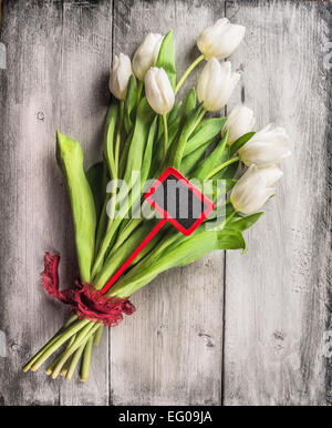 Bouquet de tulipes avec panneau rouge et ruban sur fond de bois gris, vue du dessus Banque D'Images