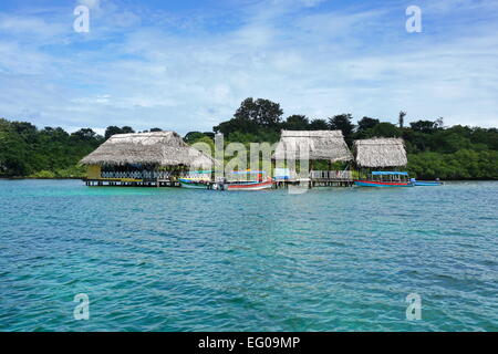 Le restaurant Tropical avec toit de chaume au-dessus de l'eau et les bateaux à quai, Caraïbes, Bocas del Toro, PANAMA, Amérique Centrale Banque D'Images