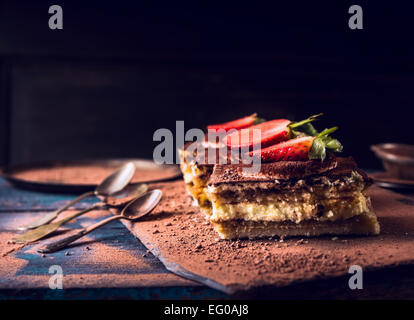 Tiramisu fraises gâteau avec trois cuillérées sur fond de bois foncé Banque D'Images