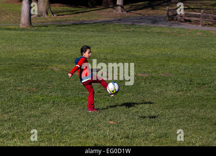 Young Hispanic boy apprendre à jouer au soccer à coups de ballon de soccer tout en jouant au football dans la région de Pioneer Park dans la ville de Novato, Californie Banque D'Images