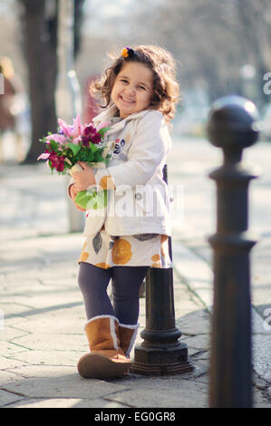 Petite fille (4-5) smiling and holding bouquet Banque D'Images