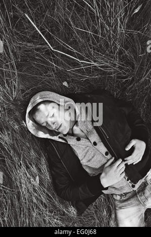 Man lying in grass sleeping Banque D'Images