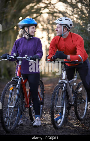 Couple Riding Mountain Bikes à travers des bois Banque D'Images