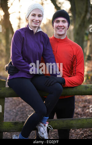 Portrait de Couple On Winter Run entre forêt Sitting on Fence Banque D'Images