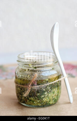 Sauce au pesto fait maison dans un bocal en verre et cuillère en porcelaine Banque D'Images