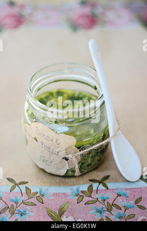 Sauce au pesto fait maison dans un bocal en verre et cuillère en porcelaine Banque D'Images