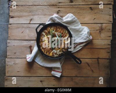 Frittata aux pommes de terre et au fromage dans la poêle sur planche de bois Banque D'Images