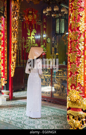 Ao dai femme portant une robe à Phuoc Hoi Quan Pagode, Cholon, Ho Chi Minh City, Vietnam Banque D'Images