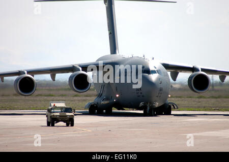 Un U.S. Air Force C-17 Globemaster III cargo) à partir de la 62e Escadre de transport aérien, déployés à partir de McChord Air Force Base, dans l'État, suit une haute mobilité alerte passagère véhicule à roues multi-usage pour une place de stationnement pendant les opérations d'aviation à la base aérienne de Karshi-Khanabad, l'Ouzbékistan, le 20 mars 2005, au cours de l'opération Enduring Freedom. Le sergent-chef. Sturkol Scott T. Banque D'Images