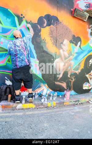 Artiste de rue au travail à 'Le Tunnel', une zone graffiti autorisé à Leake Street près de la gare de Waterloo à Londres Banque D'Images