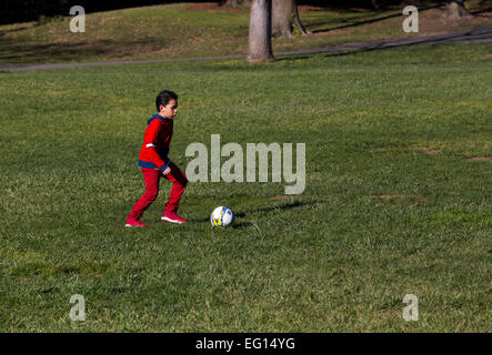 Young Hispanic boy apprendre à jouer au soccer à coups de ballon de soccer tout en jouant au football dans la région de Pioneer Park dans la ville de Novato, Californie Banque D'Images