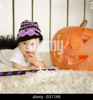 Belle fille avec le syndrome de pensivement garde doigt dans la bouche près de la big pumpkin Banque D'Images