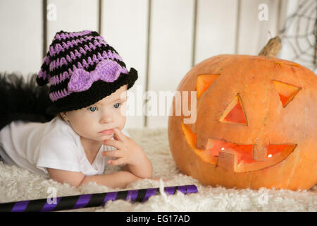 Belle fille avec le syndrome de pensivement garde doigt dans la bouche près de la big pumpkin Banque D'Images