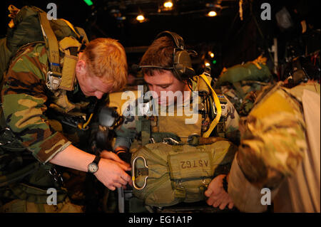 U.S. Air Force d'un membre de la 1re classe Randy Theisen, lutter contre un étudiant de montres en tant que co-workers vérifier son parachute pendant son transport sur un MC-130P Combat Shadow avions pour une mission de saisie de l'aérodrome, le 2 mars, sur la base aérienne d'Eglin, en Floride, à l'appui d'Emerald Warrior 2011. Emerald Warrior est un commandement des opérations spéciales américaines, parrainé par l'exercice multiservice conçu pour tirer parti des enseignements tirés des opérations Iraqi Freedom et Enduring Freedom à fournir formés et prêts pour les commandants de combat des forces canadiennes. Le Sgt Tech. Manuel J. MartinezReleased Banque D'Images