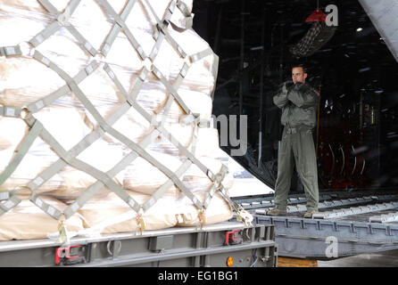 Les cadres supérieurs de l'US Air Force Brandon Lee, un aviateur 36e Escadron de transport aérien C-130 Hercules de l'arrimeur de Yokota Air Base, Japon, guides une palette avec matériel de secours humanitaire sur un avion cargo C-130 à Chitose Air Base, Japon, le 23 mars 2011. L'avion transporte six palettes transportant 15 000 livres de couvertures, d'eau et de riz à partir de la base aérienne de Matsushima, au Japon. Le s.. Robin Stanchak Banque D'Images