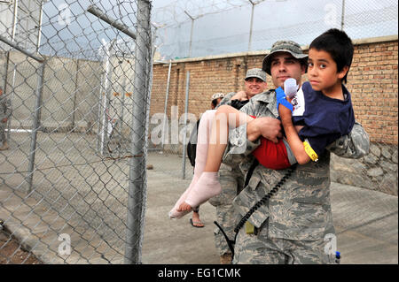 Le sergent de l'US Air Force. Billy Atherton porte un enfant afghan dans un hôpital de campagne à l'aérodrome de Bagram, en Afghanistan, le 5 mai 2011. Atherton est affecté à la 455 e Escadron expéditionnaire des activités médicales. U.S Air Force photo de l'Aviateur Senior Sheila deVera Banque D'Images