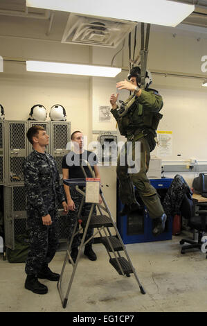 Air Force Le Capitaine Cole Davenport se bloque lors de l'équipement de survie de l'équipage de la Marine américaine hommes effectuer un contrôle de sécurité harnais de parachute Le 9 juin 2011, au Naval Air Station Whidbey Island, Washington Davenport, pour assister à un cours de formation de la marine, est un officier de guerre électronique affecté à l'Escadron d'attaque électronique Voilure fixe 129. Le s.. Gina Chiaverotti-Paige Banque D'Images