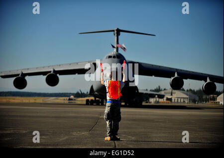 U.S. Air Force d'un membre de la 1re classe Christopher Cramera maréchaux un U.S. Air Force avion cargo C-5 Galaxy à partir de la 60e Escadre de mobilité aérienne Travis Air Force Base, en Californie, dans sa place de parking sur la ligne de vol comme il arrive pour l'aéromobilité Rodeo 2011 à Joint Base Lewis-McChord, dans l'État, le 23 juillet. Le s.. Nicholas Pilch Banque D'Images