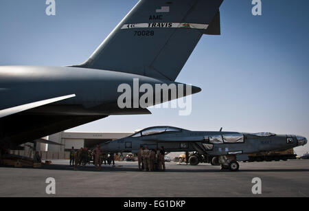 Les membres du 451e Escadron de préparation logistique expéditionnaire port aérien et vol 22e Escadron de transport aérien se préparent à charger un Marine américain F/A-18 Super Hornet de l'US Air Force sur un C-5 Galaxy cargo) sur l'aérodrome de Kandahar, Afghanistan, le 18 août 2011. L'avion ayant transporté au states et réparés seront probablement coûté un tiers de ce qu'un nouvel avion coûterait. Carajal Senior Airman David Banque D'Images